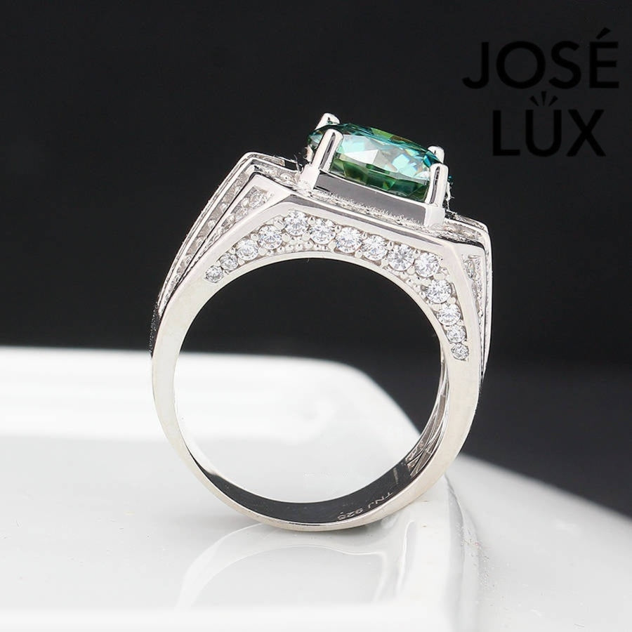 Substantial sterling silver men's ring featuring a 4-carat round green moissanite encircled by a cushion-shaped halo. Wide band with alternating rows of round and baguette stones creates impressive depth and dimension.
