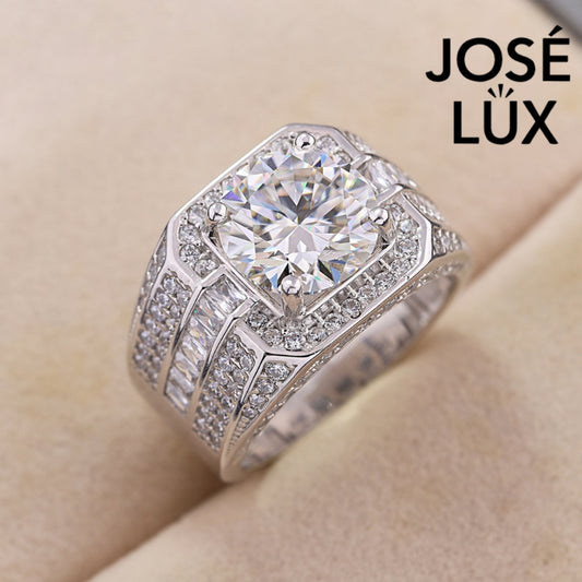 Striking men's ring in sterling silver showcases a brilliant 4-carat round moissanite within an octagonal double halo. Wide band features tiered baguette channels and pavé rows for exceptional sparkle and dimensional design.