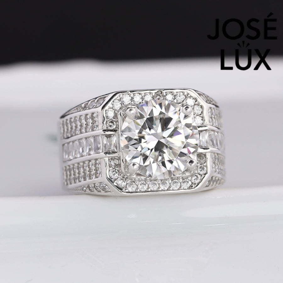Striking men's ring in sterling silver showcases a brilliant 4-carat round moissanite within an octagonal double halo. Wide band features tiered baguette channels and pavé rows for exceptional sparkle and dimensional design.