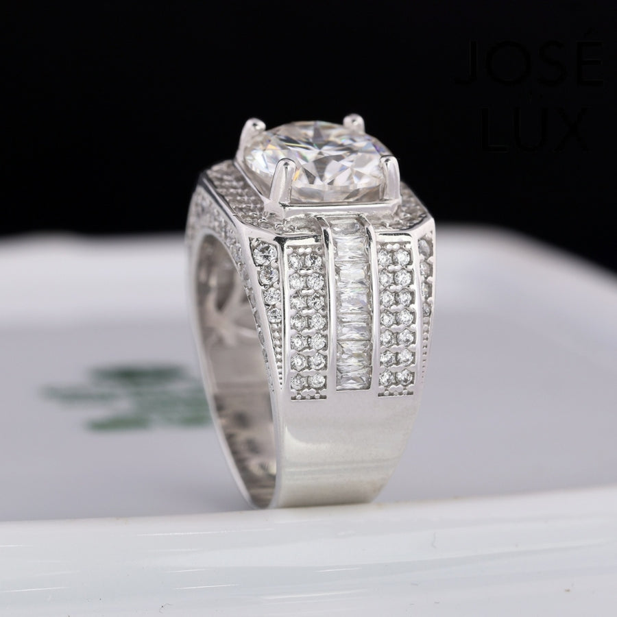 Striking men's ring in sterling silver showcases a brilliant 4-carat round moissanite within an octagonal double halo. Wide band features tiered baguette channels and pavé rows for exceptional sparkle and dimensional design.