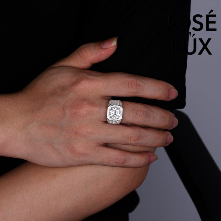 Striking men's ring in sterling silver showcases a brilliant 4-carat round moissanite within an octagonal double halo. Wide band features tiered baguette channels and pavé rows for exceptional sparkle and dimensional design.