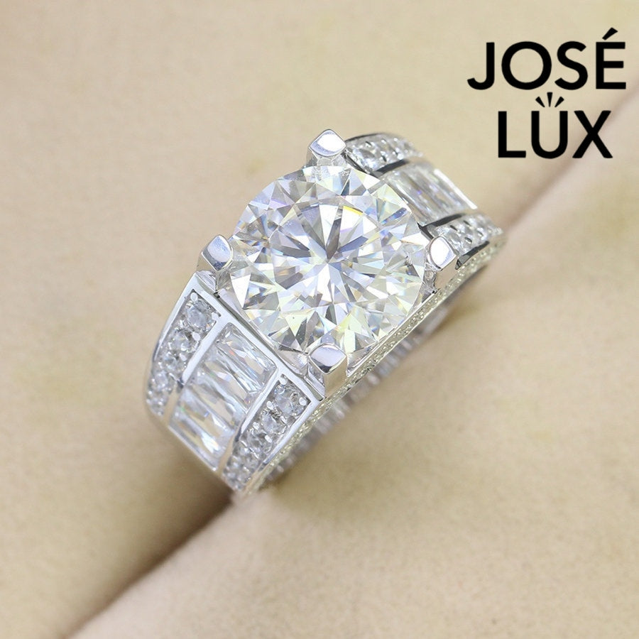 Classic men's ring in sterling silver showcases a brilliant 4-carat round moissanite in four-prong setting. Wide triple-row band features vertical baguette channels bordered by pavé stones for timeless sophistication.