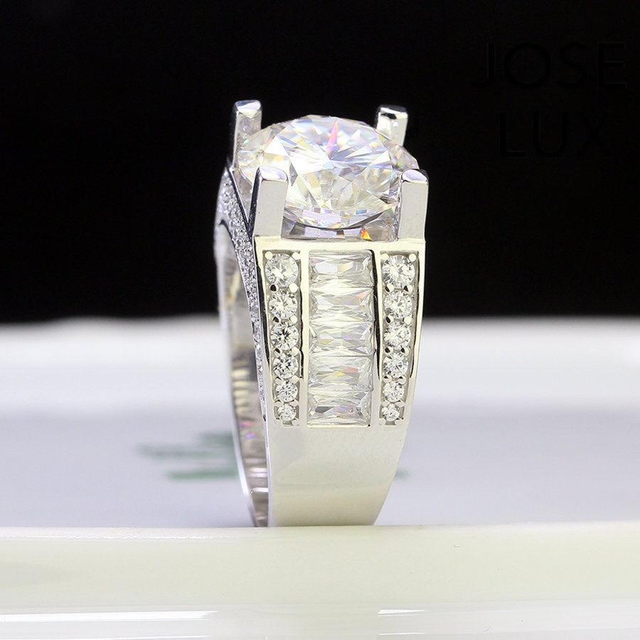 Classic men's ring in sterling silver showcases a brilliant 4-carat round moissanite in four-prong setting. Wide triple-row band features vertical baguette channels bordered by pavé stones for timeless sophistication.