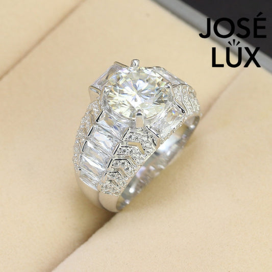 Commanding men's ring in sterling silver features a brilliant 4-carat round moissanite in six-prong setting. Wide band showcases graduated baguette-cut stones in chevron pattern with pavé accents for dimensional impact.