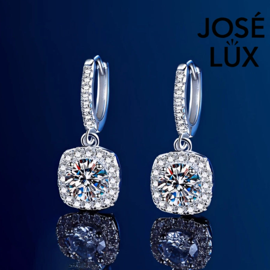 Elegant cushion-cut moissanite with sparkling halo setting in sterling silver. Graceful drop design adds sophisticated movement and brilliant fire for timeless everyday elegance.