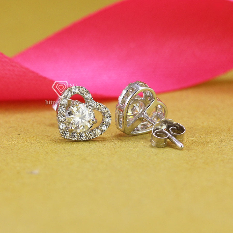 Romantic heart-shaped moissanite with sparkling halo setting in sterling silver. Sweet love-inspired design delivers brilliant fire and scintillation for charming everyday elegance.