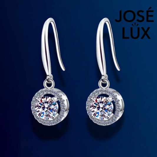 Elegant round moissanite with sparkling halo setting in sterling silver. Graceful dangle design adds beautiful movement and brilliant fire for sophisticated everyday wear.