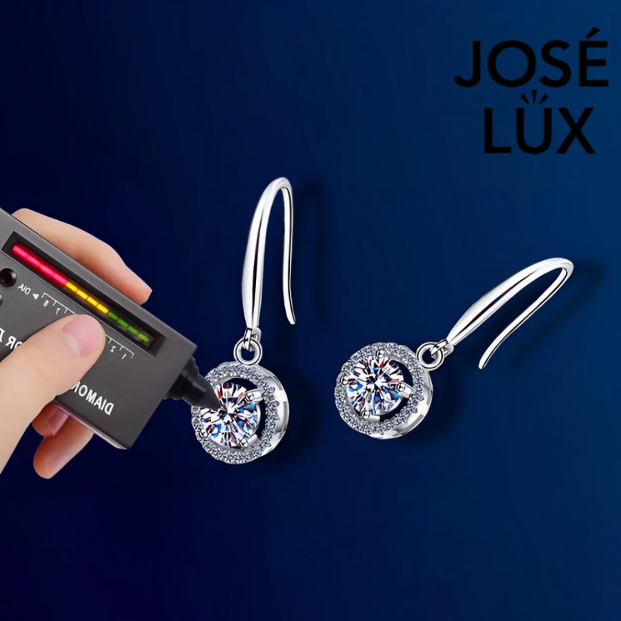 Elegant round moissanite with sparkling halo setting in sterling silver. Graceful dangle design adds beautiful movement and brilliant fire for sophisticated everyday wear.