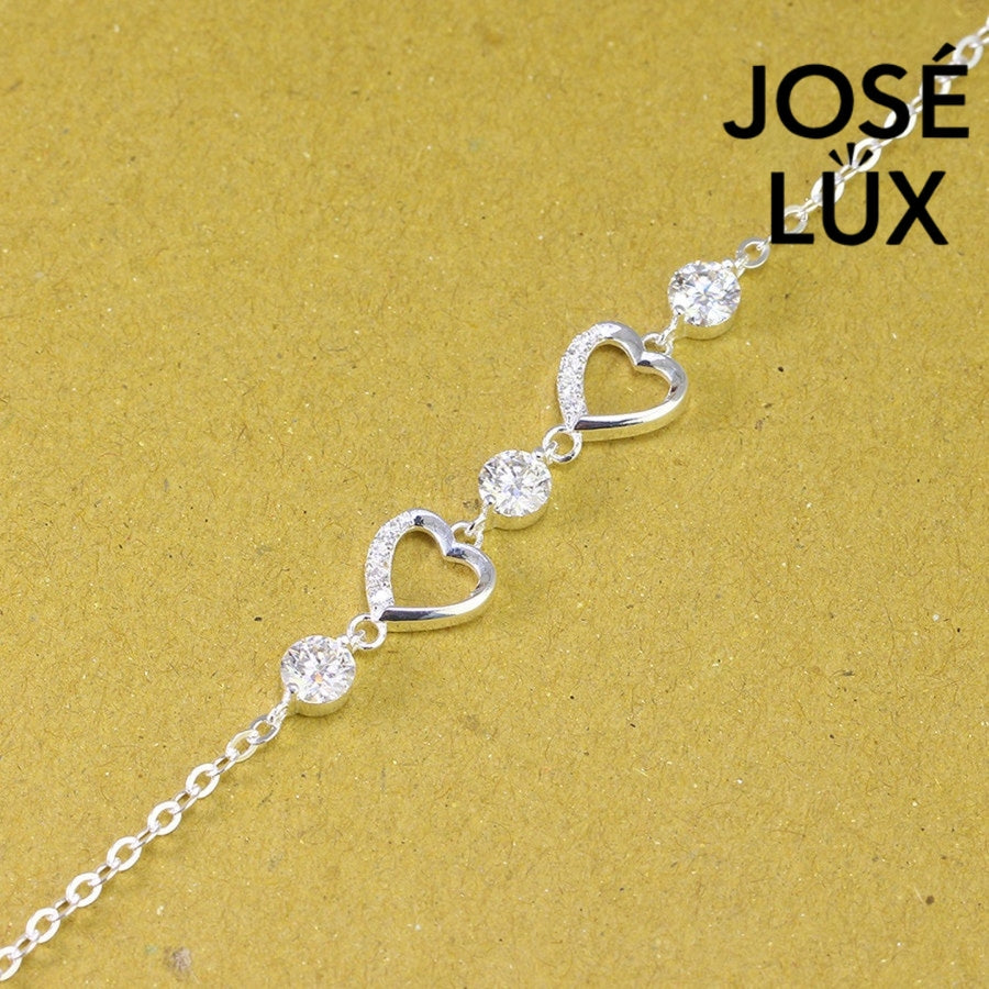 Pave heart station moissanite bracelet in sterling silver features two romantic heart motifs with three brilliant stones totaling 1.53 carats on cable chain.